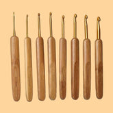 A set of eight bamboo handle crochet hooks with metal hook heads, displayed in a row against a beige background.